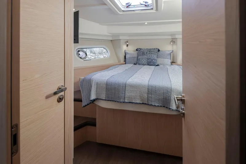 4 My Valentine Yacht Photos Pics Cozy bedroom in 2022 Beneteau Swift Trawler 41 with striped bedding and porthole window.