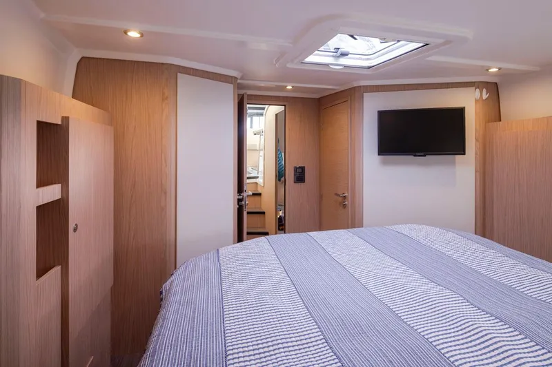 4 My Valentine Yacht Photos Pics Interior of 2022 Beneteau Swift Trawler 41 cabin with bed, TV, and wood paneling.