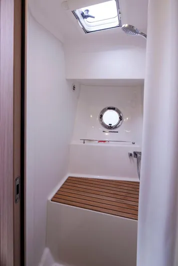 4 My Valentine Yacht Photos Pics 2022 Beneteau Swift Trawler 41 shower area with wooden floor and porthole window.