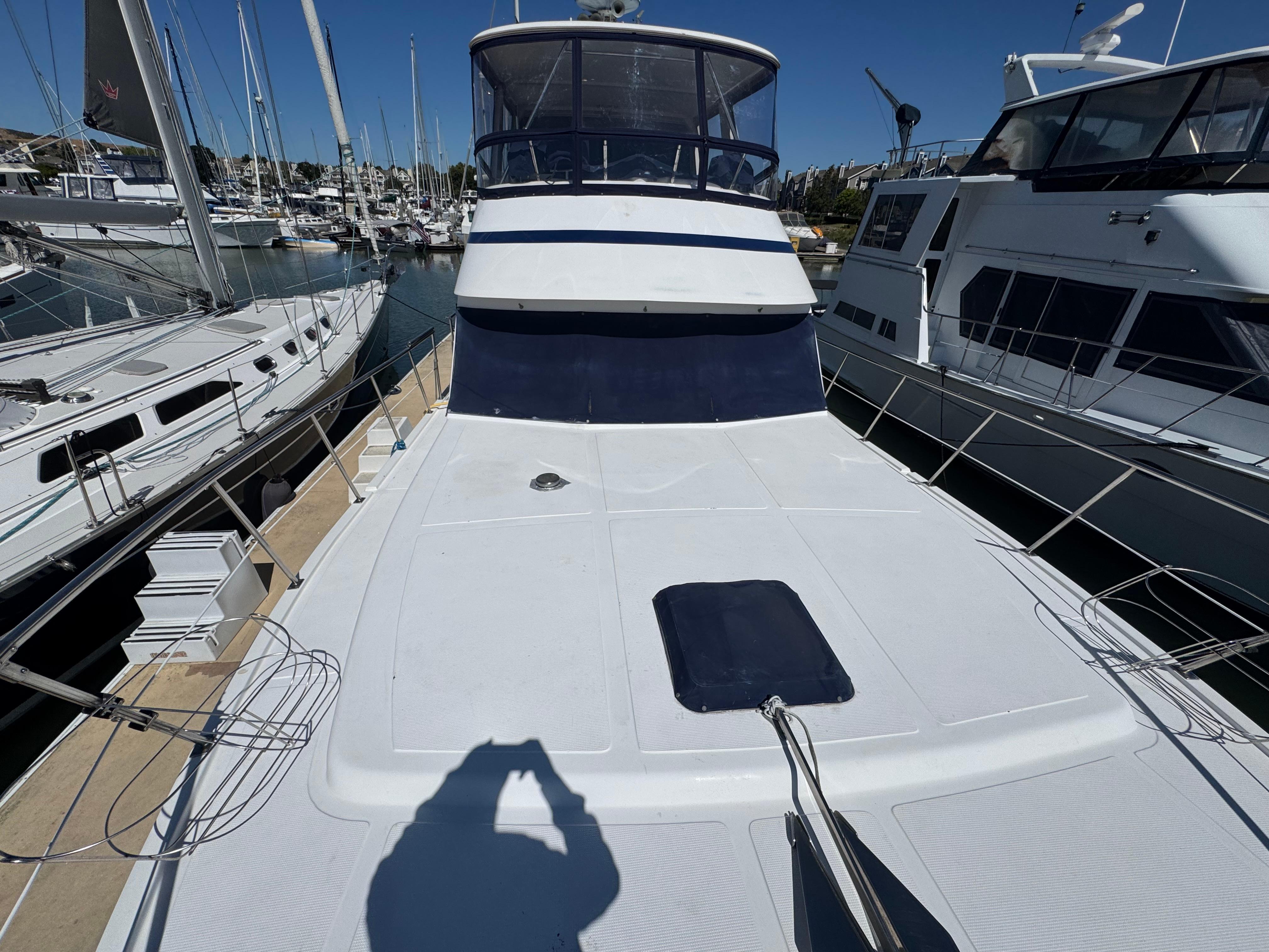 1990 Nova 48 yacht docked at marina, surrounded by other boats under clear blue sky.