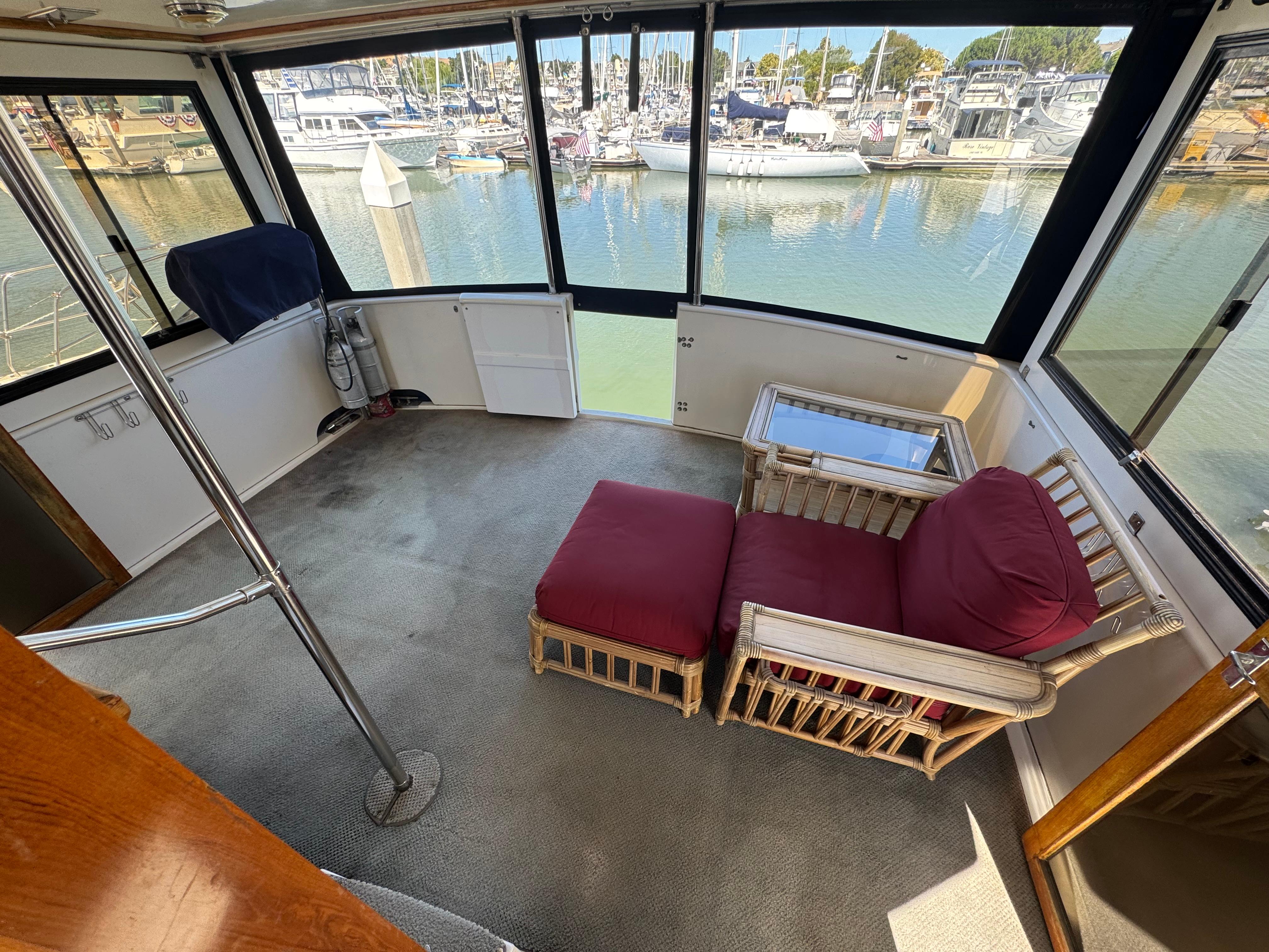 Interior of a 1990 Nova 48 yacht with red cushioned seating and marina view.