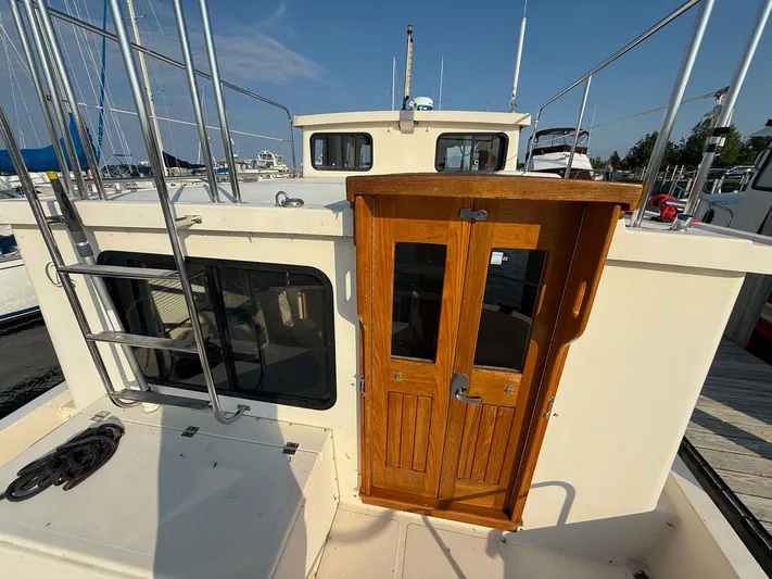 Emerald Isle Yacht Photos Pics 1998 Nordic Tug Trawler with wooden doors and metal ladder, docked at marina.
