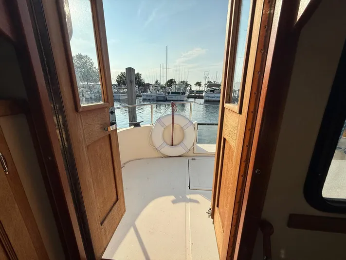 Emerald Isle Yacht Photos Pics 1998 Nordic Tug Trawler deck view with open wooden doors and marina backdrop.
