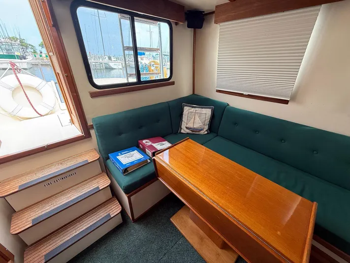 Emerald Isle Yacht Photos Pics Cozy interior of 1998 Nordic Tug Trawler with green seating and wooden table.