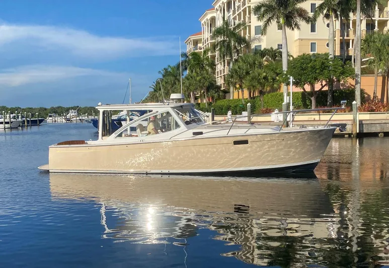 Glory Yacht Photos Pics 2006 MJM 34z Express HT yacht docked in a sunny marina, surrounded by palm trees.