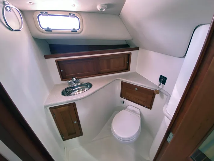 Glory Yacht Photos Pics 2006 MJM 34z Express HT boat bathroom with sink, toilet, and wooden cabinets.