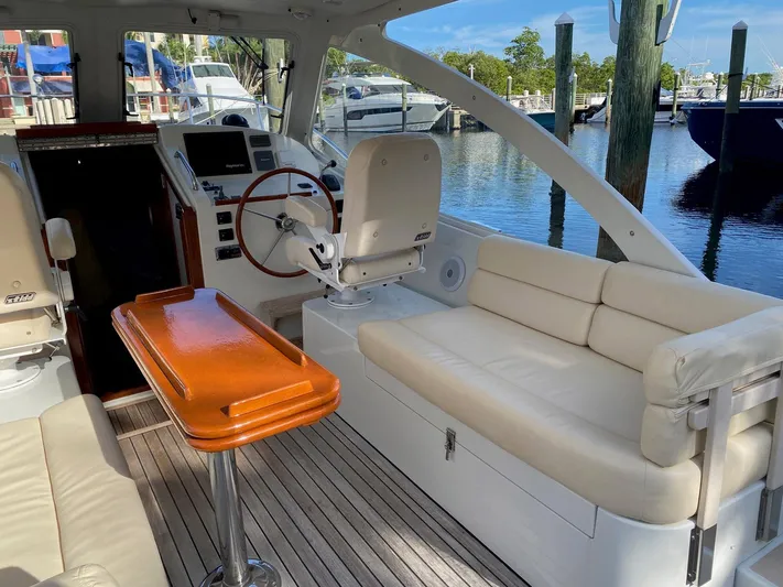 Glory Yacht Photos Pics 2006 MJM 34z Express HT boat interior with helm, seating, and wooden table.