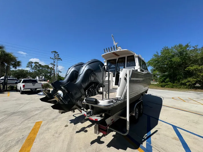  Yacht Photos Pics 2024 Cutwater C-288 Coupe boat on trailer, featuring dual outboard motors, parked outdoors.