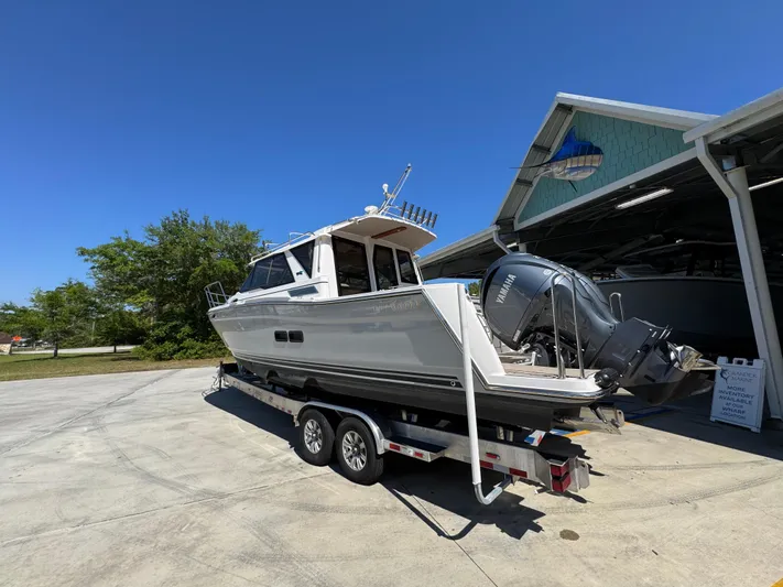  Yacht Photos Pics 2024 Cutwater C-288 Coupe boat on trailer, parked outdoors under clear blue sky.