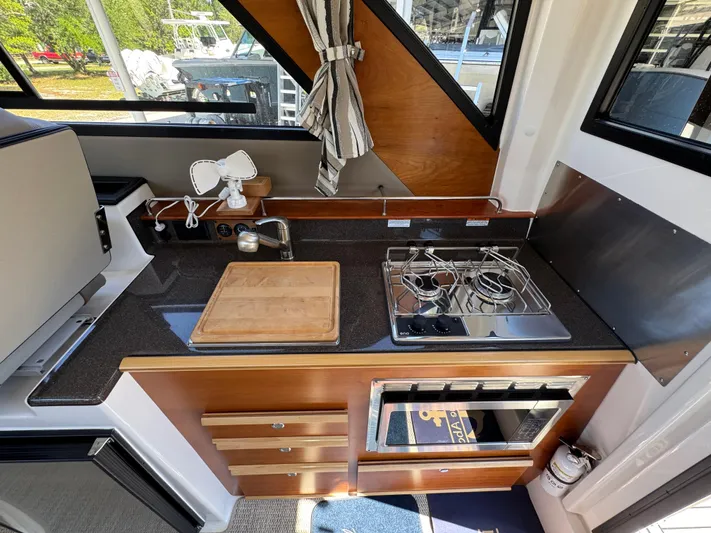  Yacht Photos Pics 2024 Cutwater C-288 Coupe kitchen with stove, sink, and wooden cabinetry.