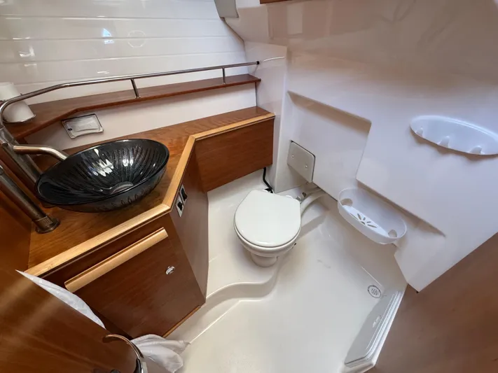  Yacht Photos Pics 2024 Cutwater C-288 Coupe bathroom with modern sink, toilet, and wooden cabinetry.