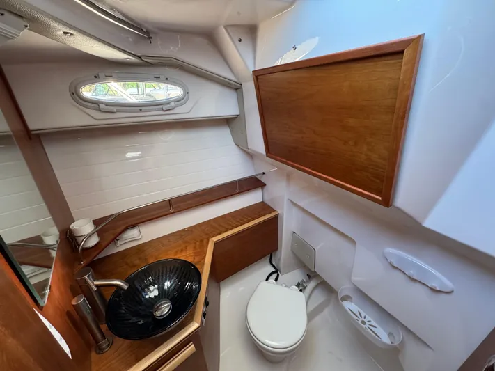  Yacht Photos Pics 2024 Cutwater C-288 Coupe bathroom with modern sink, toilet, and wooden cabinetry.