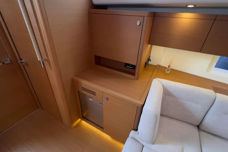  Yacht Photos Pics Interior of 2017 Grand Soleil 52 LC yacht with modern wood cabinetry and beige sofa.