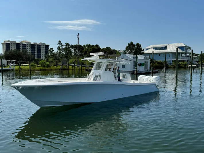  Yacht Photos Pics 2023 Invincible 36 Open Fisherman boat on calm water near docks and houses.