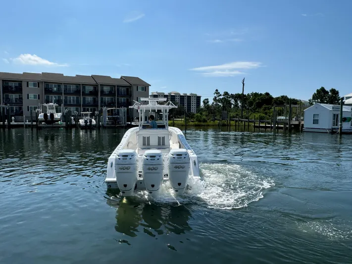  Yacht Photos Pics 2023 Invincible 36 Open Fisherman boat with triple engines on a calm waterfront.