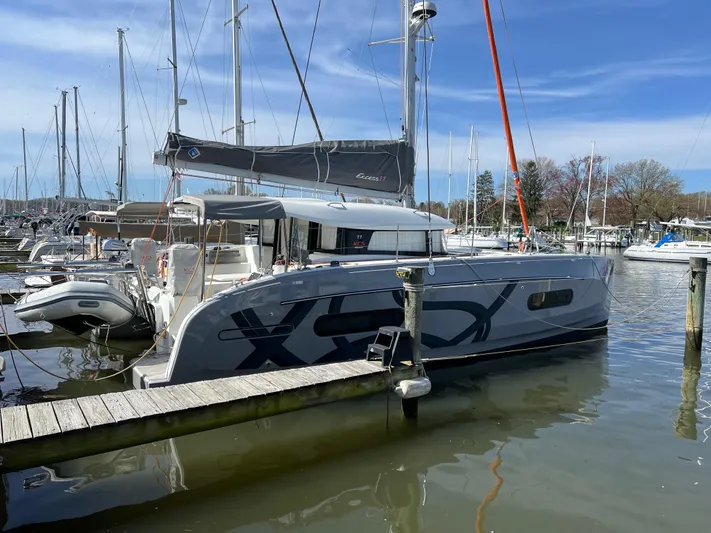 Sia Yacht Photos Pics 2022 Excess XCS 11 catamaran docked in a marina, clear sky background.