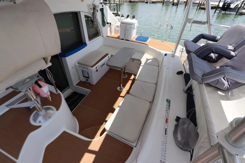  Yacht Photos Pics Spacious deck of 2001 Lagoon 380 catamaran with seating and table, docked by the water.