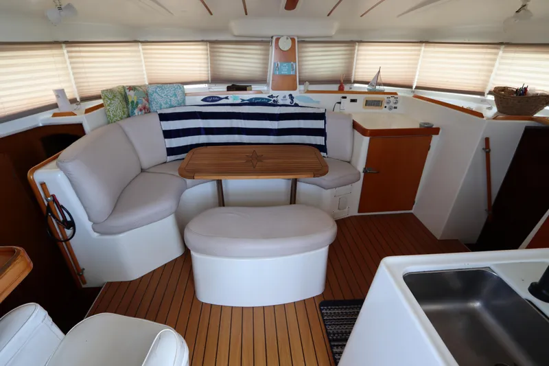  Yacht Photos Pics Interior of 2001 Lagoon 380 catamaran with cozy seating and wooden table.