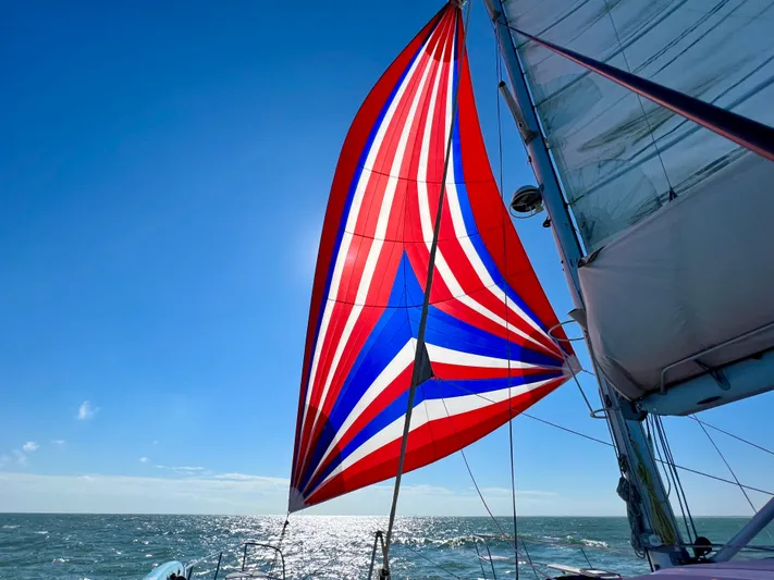 Walkabout Yacht Photos Pics Royal Cape Catamarans 530 sailing with vibrant red, white, and blue spinnaker, 2019 model.
