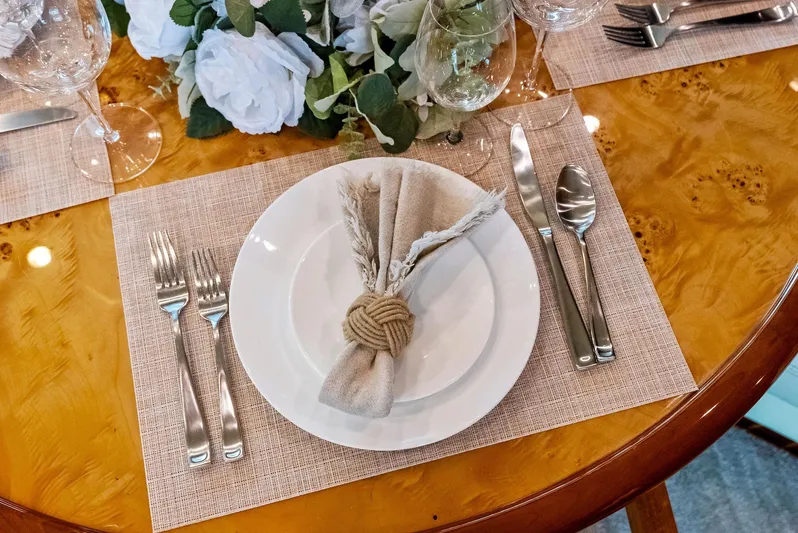 Tortuga Yacht Photos Pics Elegant dining setup on Monte Fino 82 yacht, featuring white plates and silver cutlery.