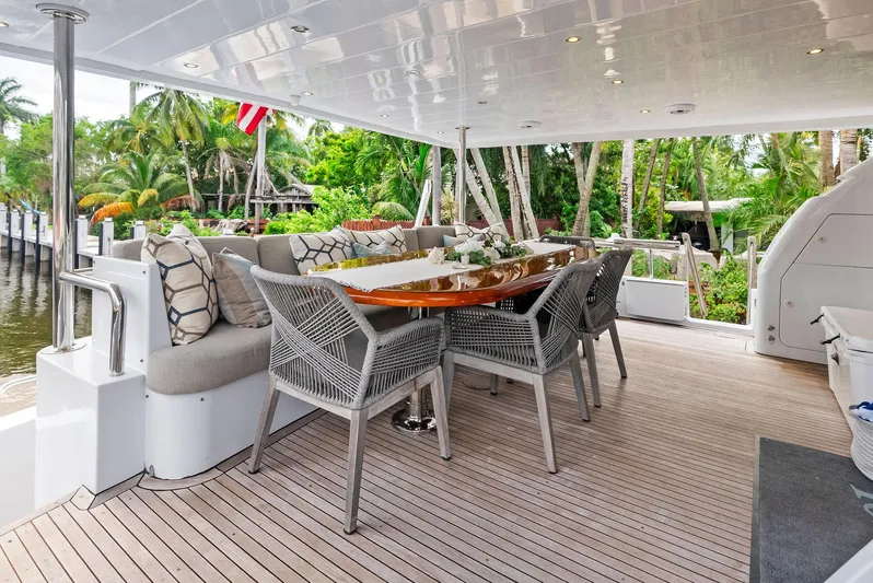 Tortuga Yacht Photos Pics Luxurious outdoor dining area on 1999 Monte Fino 82 yacht, surrounded by lush greenery.