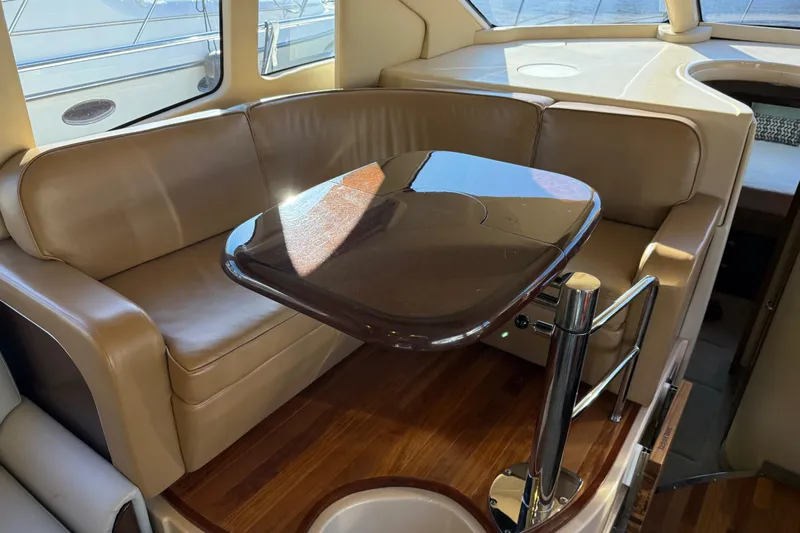  Yacht Photos Pics Luxurious interior of 2006 Sea Ray 44 Sedan Bridge with leather seating and wooden table.