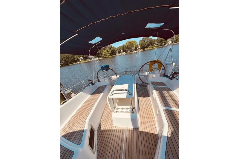 Bluefin Yacht Photos Pics 2008 Jeanneau Sun Odyssey 45 DS sailboat cockpit with wooden deck and canopy on a serene lake.