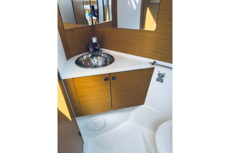 Bluefin Yacht Photos Pics Compact bathroom with wooden cabinetry and stainless steel sink on Jeanneau Sun Odyssey 45 DS yacht.