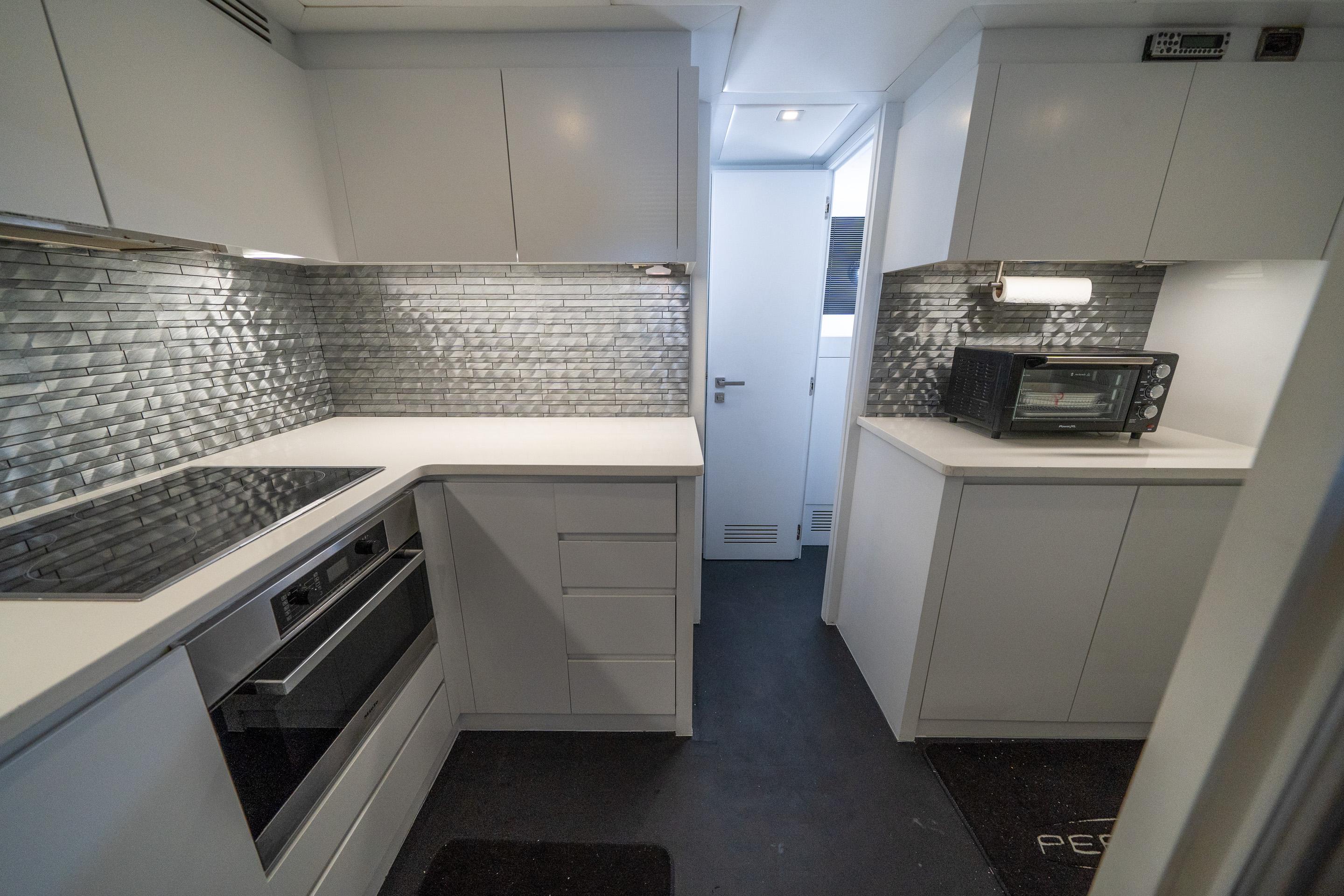 Modern kitchen interior of 2010 Pershing 80 yacht with sleek cabinetry and metallic backsplash.
