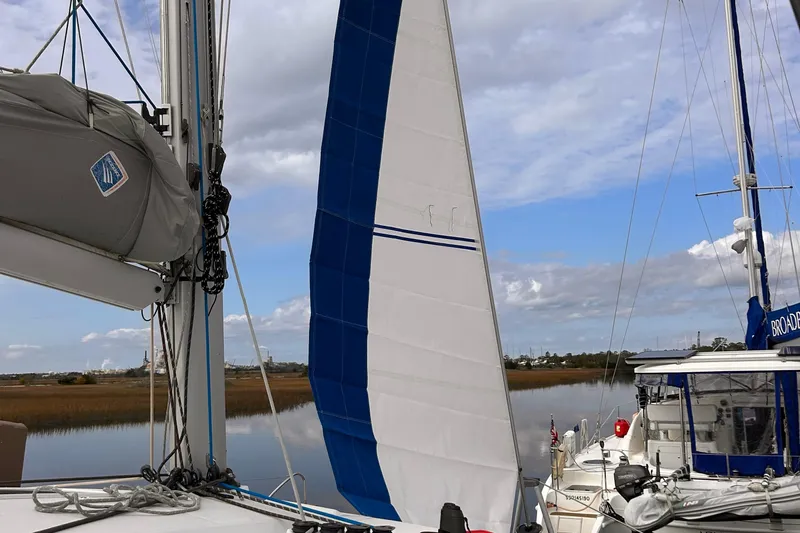 Sabai Sabai Yacht Photos Pics 2018 Fountaine Pajot Lucia 40 catamaran with sails, docked by a serene waterway.