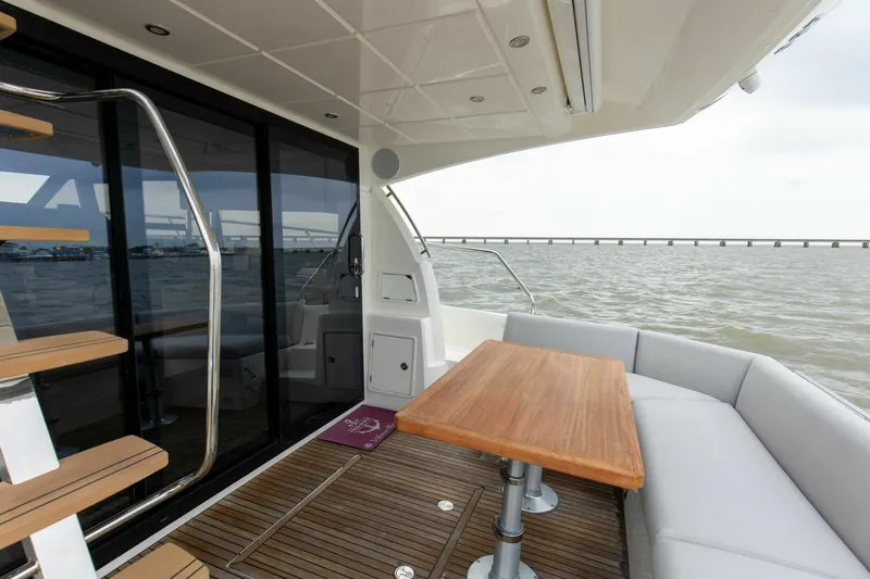 Pass-n-bye Yacht Photos Pics Prestige 460 Flybridge 2023 yacht deck with seating and table, overlooking the ocean.