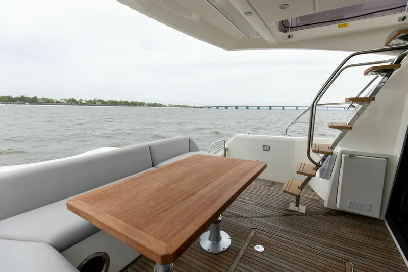 Pass-n-bye Yacht Photos Pics Prestige 460 Flybridge 2023 yacht deck with wooden table, seating, and water view.