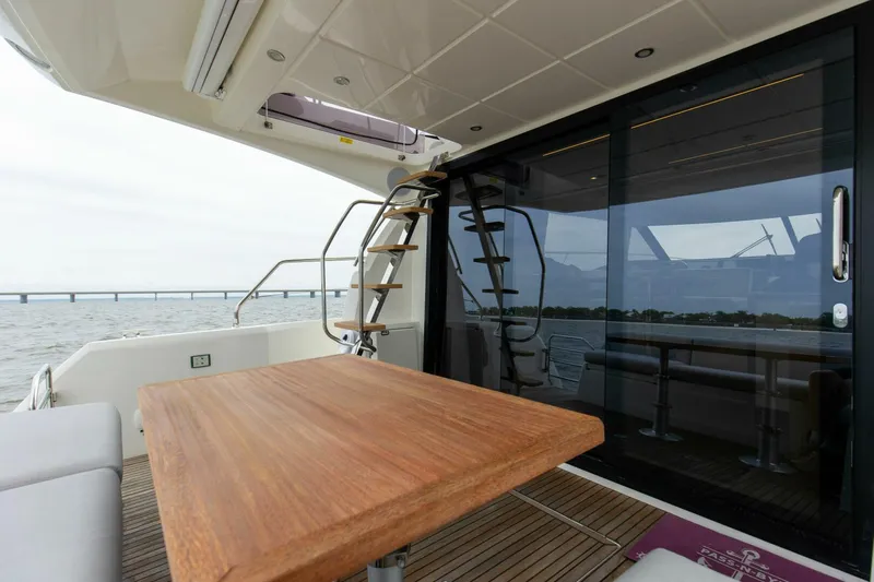 Pass-n-bye Yacht Photos Pics Prestige 460 Flybridge 2023 yacht with wooden table and glass doors, overlooking the sea.