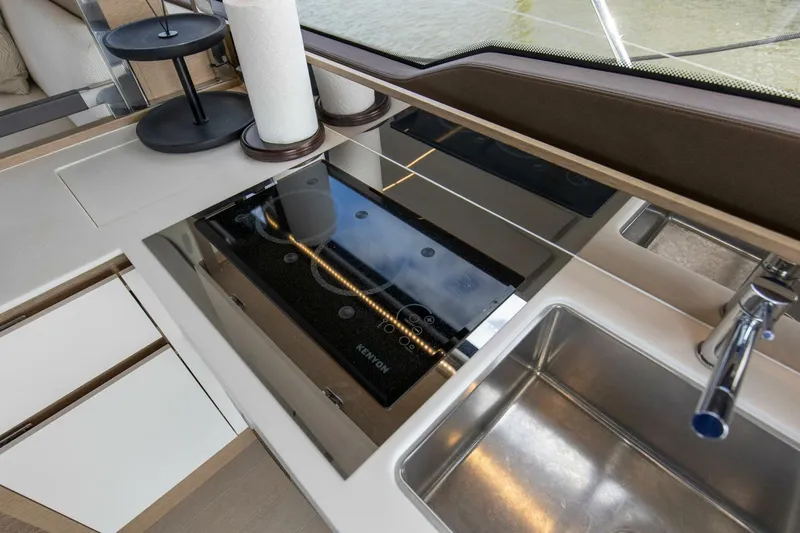 Pass-n-bye Yacht Photos Pics Modern kitchen area on 2023 Prestige 460 Flybridge yacht with sleek sink and stove.