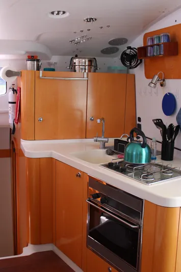 Quelle Belle Vie Yacht Photos Pics Modern kitchen in 2008 Fountaine Pajot Mahe 36 catamaran with wooden cabinets and appliances.