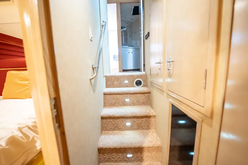 Hatts Off Yacht Photos Pics Interior stairs of 1998 Hatteras 74 Cockpit Motor Yacht, featuring carpeted steps and ambient lighting.