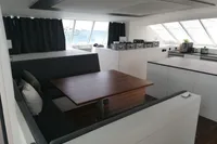 Modern interior of 2023 Custom 22m Catamaran with dining area and panoramic windows.