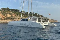 Custom 22m Catamaran 2023 sailing near rocky coastline under clear sky.