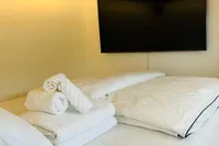 Luxurious bedroom on 2023 Custom 22m Catamaran with modern decor and large TV.