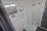 Modern bathroom on 2023 Custom 22m Catamaran with glass shower and sleek fixtures.