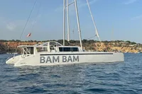 Custom 22m Catamaran "BAM BAM" sailing near rocky coastline, 2023 model.