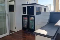 Modern interior of 2023 Custom 22m Catamaran with seating, fridge, and stairs.