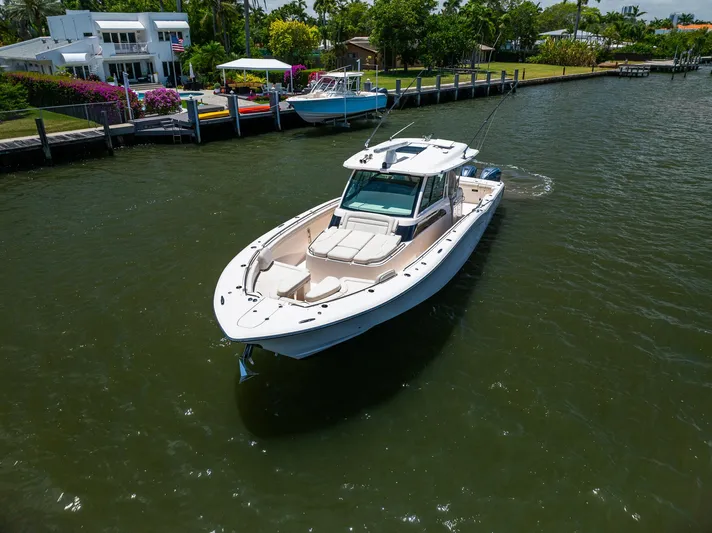  Yacht Photos Pics 2019 Grady-White Canyon 456 boat cruising on a calm river near a dock.