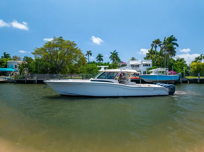  Yacht Photos Pics 2019 Grady-White Canyon 456 boat cruising on a sunny day near waterfront homes.
