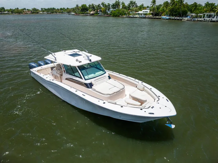  Yacht Photos Pics 2019 Grady-White Canyon 456 boat on calm water, surrounded by lush greenery.