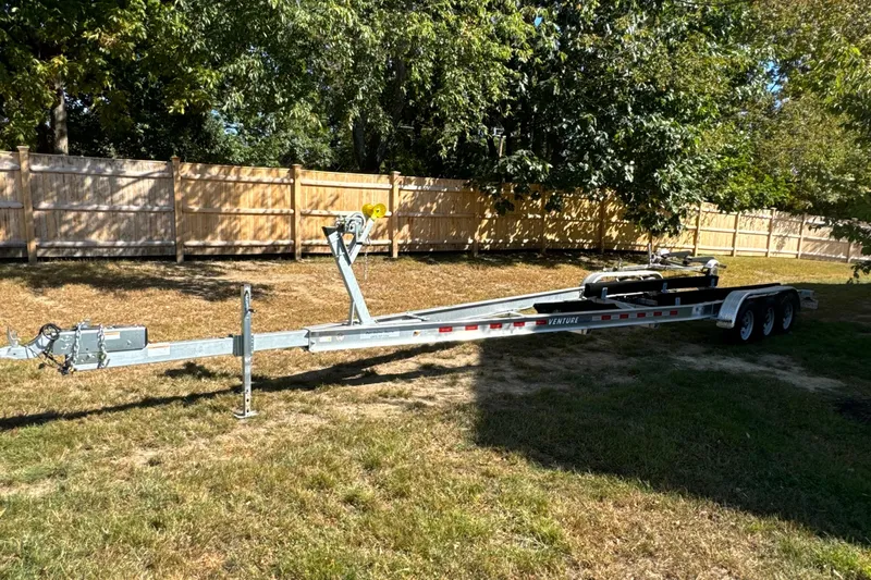  Yacht Photos Pics Trailer for 2023 Sailfish 312 CC boat parked on grass near wooden fence.