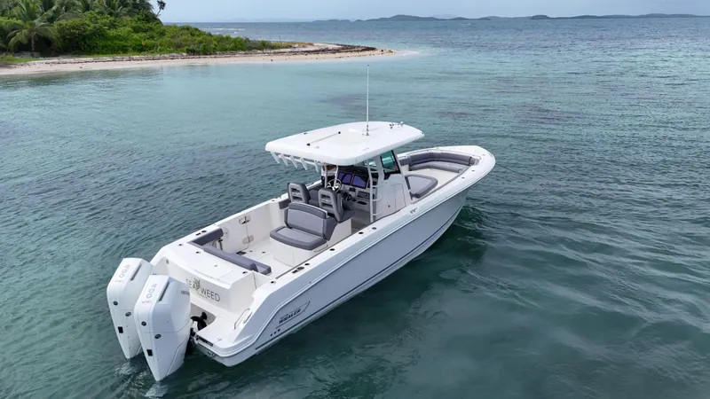  Yacht Photos Pics 2025 Boston Whaler 330 Outrage boat on calm tropical waters near a small island.