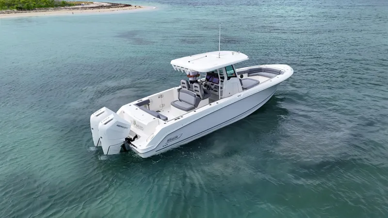  Yacht Photos Pics 2025 Boston Whaler 330 Outrage boat on clear blue water near a small island.