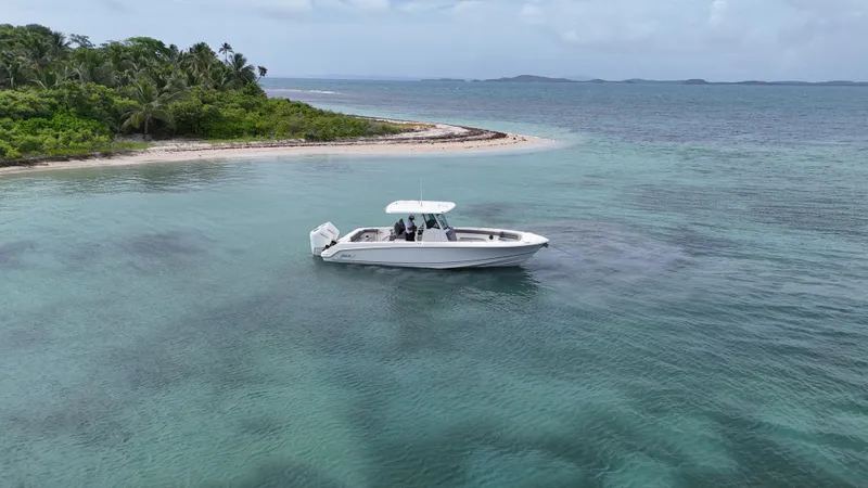  Yacht Photos Pics 2025 Boston Whaler 330 Outrage cruising near tropical island with clear blue waters.