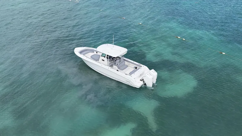  Yacht Photos Pics 2025 Boston Whaler 330 Outrage boat on clear turquoise water, aerial view.